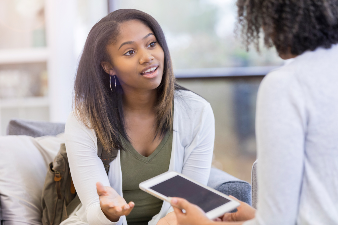 Teenage girl talks with high school counselor